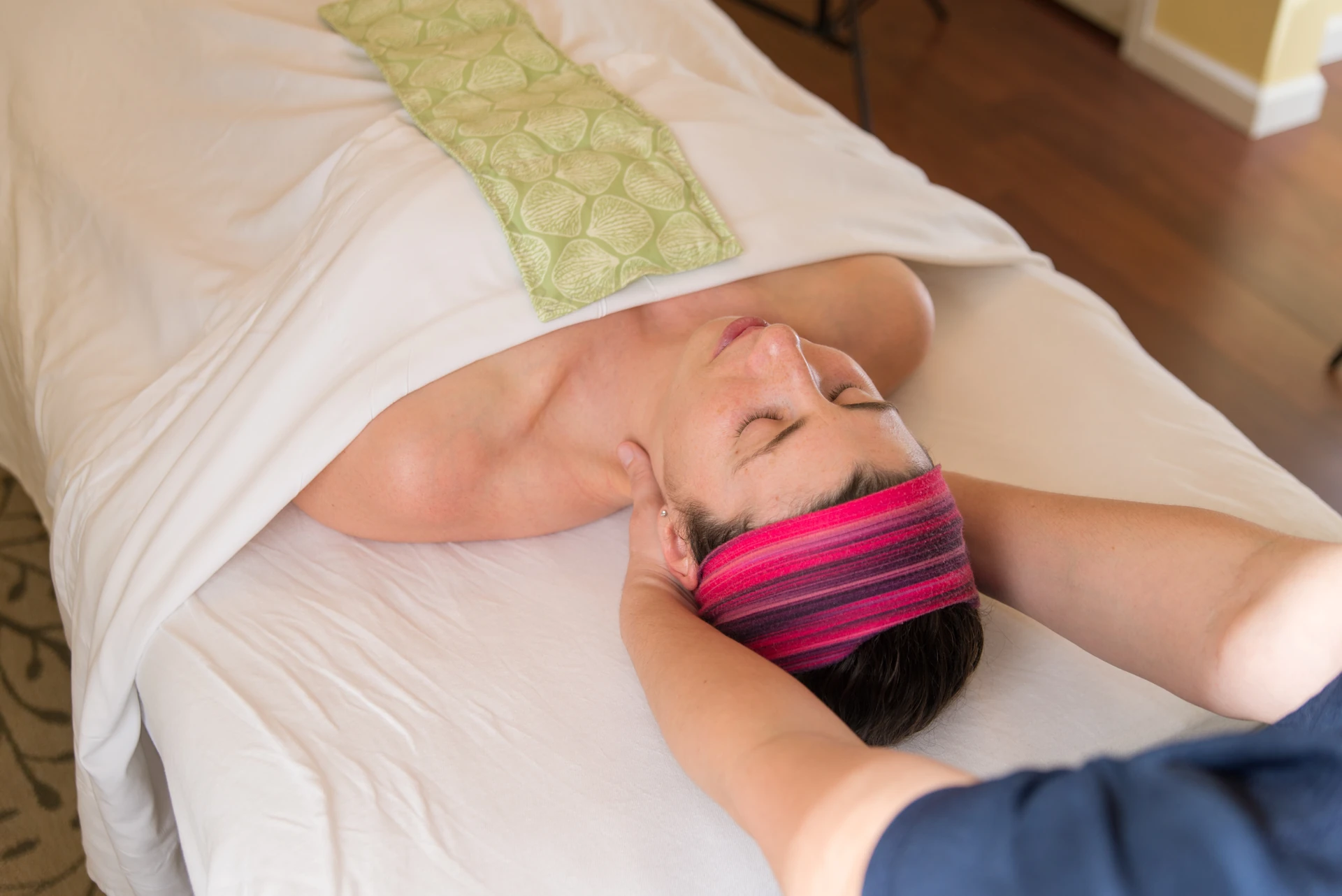 A massage therapist gently cradles a patient's head and neck during a calm medical massage session