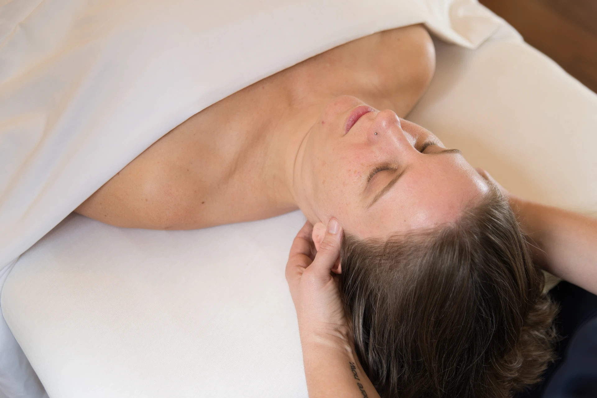 A massage therapist gently holds and supports a patient's neck during a restful medical massage session