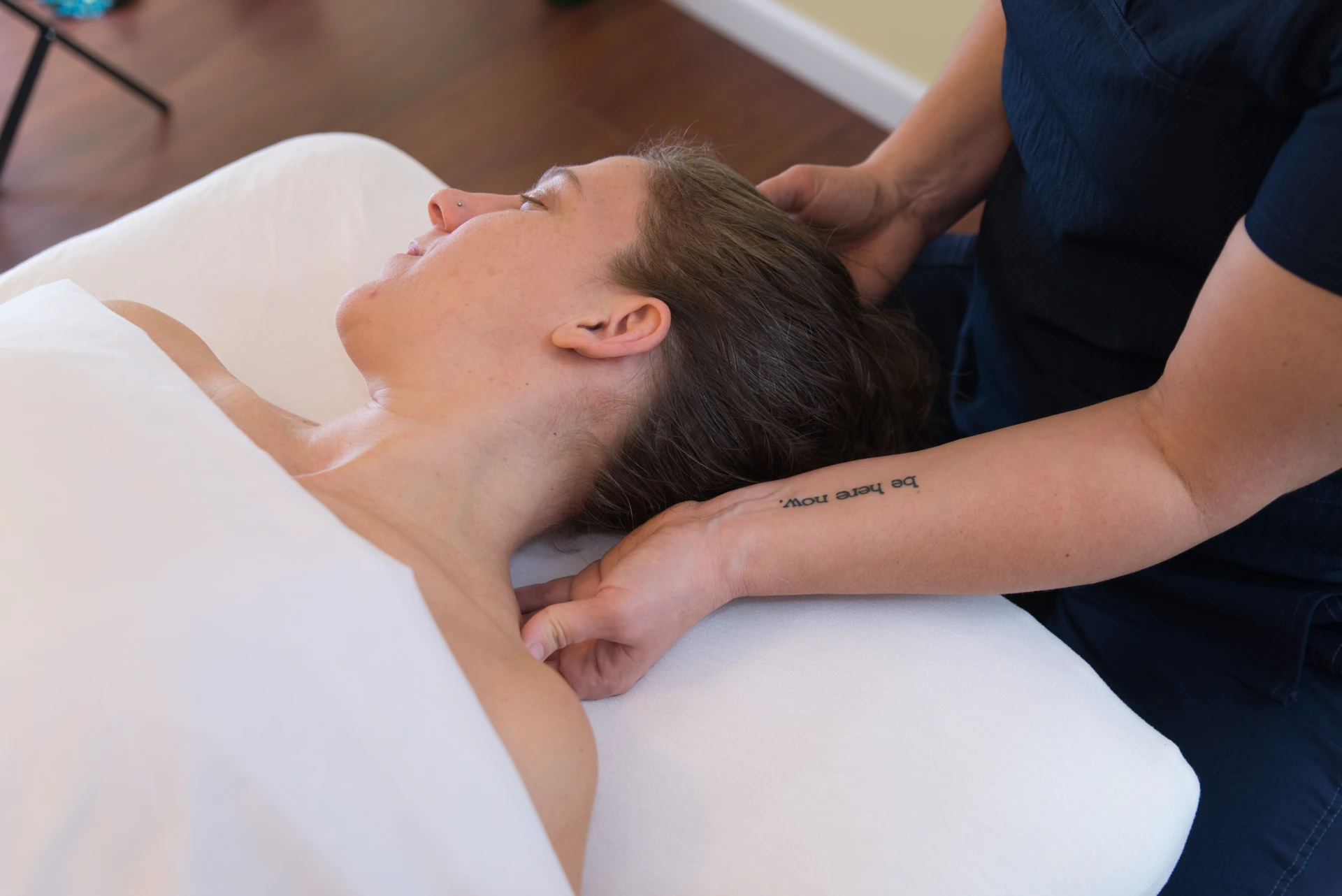 A massage therapist supports a patient's head and neck at the start of a calm medical massage session