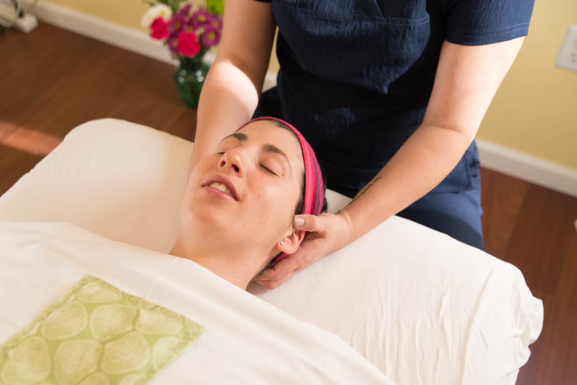 A massage therapist supports a patient's head and neck in the treatment room during a calm medical massage session.